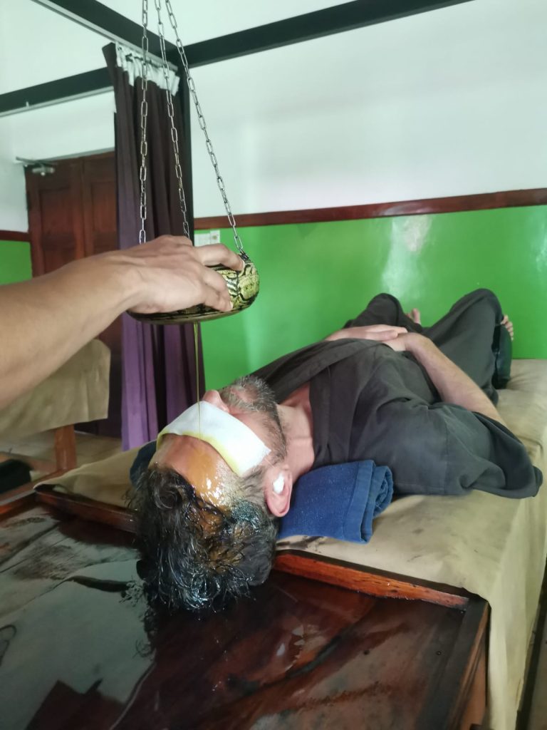 un mio amico durante la pratica di Shirodara che consiste in colata di olio tiepido sulla fronte