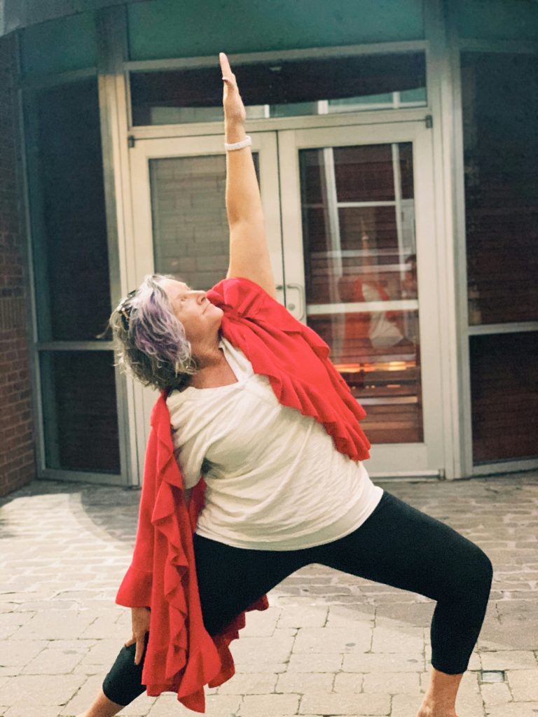Donna over 50 che pratica Yoga davanti alla porta di casa