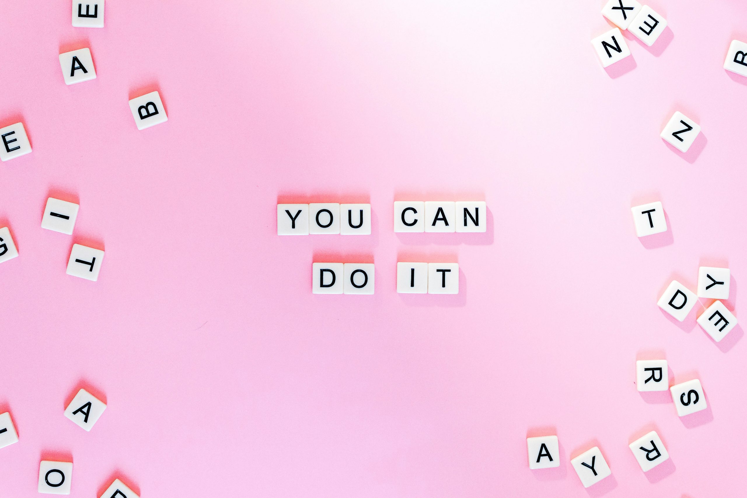 Lettere del gioco Scarabeo su fondo rosa "you can do it"