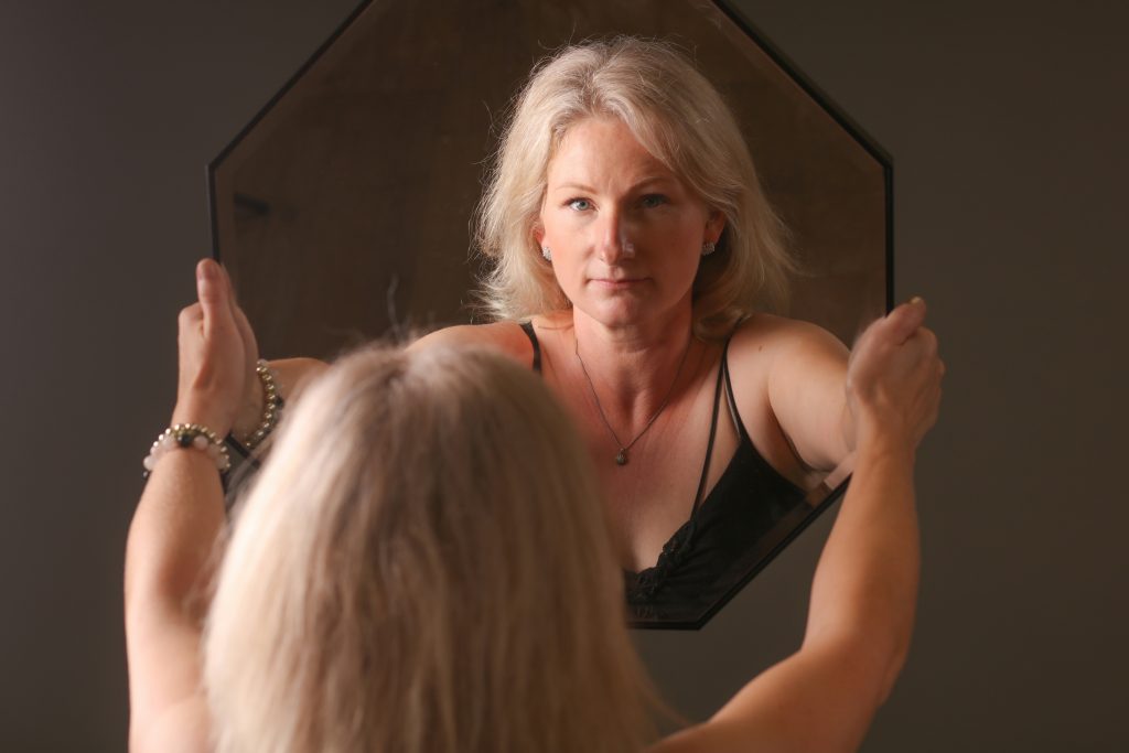 Donna che si guarda allo specchio che sorregge